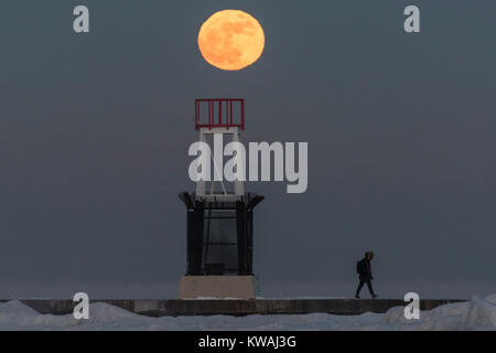 Chicago, USA. 1 Jan, 2018. Ein Mann geht über die Anlegestelle am Eis bedeckt North Avenue Beach als supermoon auf einer der kältesten Tage des neuen Jahres seit Jahrzehnten steigt. Der Mond ist an seinem nächsten Punkt, dem Perigäum, auf der Erde während seiner monatlichen Orbit und erscheint 30 % mehr Helligkeit und 14 % größer. Januar 2018 sieht eine supermoon als "Wolf Moon' am 1. Januar und ein "Blue Moon" am 31. Januar bekannt. Credit: Stephen Chung/Alamy leben Nachrichten Stockfoto