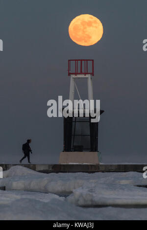 Chicago, USA. 1 Jan, 2018. Ein Mann geht über die Anlegestelle am Eis bedeckt North Avenue Beach als supermoon auf einer der kältesten Tage des neuen Jahres seit Jahrzehnten steigt. Der Mond ist an seinem nächsten Punkt, dem Perigäum, auf der Erde während seiner monatlichen Orbit und erscheint 30 % mehr Helligkeit und 14 % größer. Januar 2018 sieht eine supermoon als "Wolf Moon' am 1. Januar und ein "Blue Moon" am 31. Januar bekannt. Credit: Stephen Chung/Alamy leben Nachrichten Stockfoto