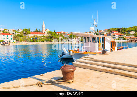 Angeln boot Verankerung in Sumartin Port mit schönen alten Kirche im Hintergrund, Insel Brac, Kroatien Stockfoto