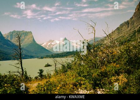 Ein Fluss schneidet durch eine Landschaft mit steilen Berghängen und niedriger Vegetation bei Saint Marys See, Glacier National Park, Montana, 1960. Stockfoto