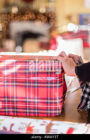 Nahaufnahme von Frau verpacken Weihnachten Geschenk am Tisch mit Bokeh leuchtet Stockfoto