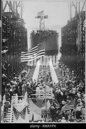 Die aufwändige Einführung des US Naval Vessel, Quistconck, an der Hog Island Werft, mit Präsident Woodrow Wilson und seiner Frau Wilson stand neben einem hohen uns Fahnenmast auf der Plattform, mit Massen von Menschen klatschen und wehenden Fahnen und Naval stehende Männer auf dem Achterdeck des Schiffes, Philadelphia, Pennsylvania, 1918. Mit freundlicher Genehmigung der nationalen Archive. Stockfoto