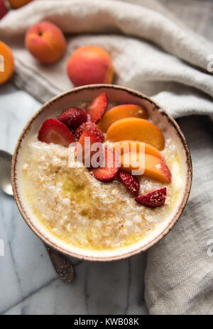 Warmes Müsli Schüssel serviert mit frischen Pfirsichen und Erdbeeren für ein gesundes Frühstück Stockfoto