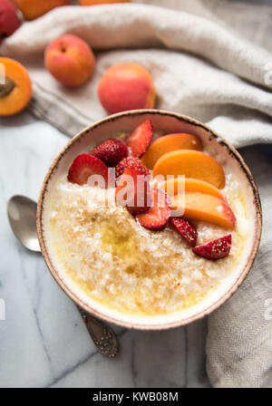 Warmes Müsli Schüssel serviert mit frischen Pfirsichen und Erdbeeren für ein gesundes Frühstück Stockfoto