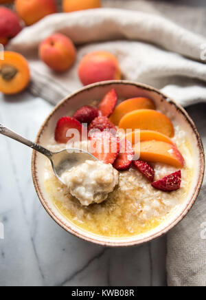 Warmes Müsli Schüssel serviert mit frischen Pfirsichen und Erdbeeren für ein gesundes Frühstück Stockfoto