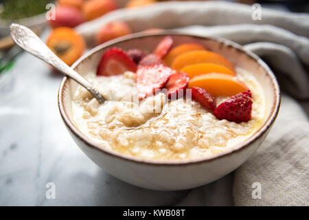 Warmes Müsli Schüssel serviert mit frischen Pfirsichen und Erdbeeren für ein gesundes Frühstück Stockfoto