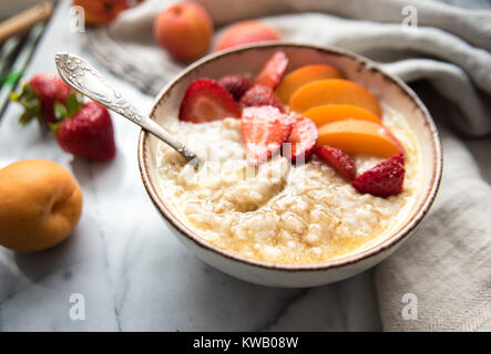 Warmes Müsli Schüssel serviert mit frischen Pfirsichen und Erdbeeren für ein gesundes Frühstück Stockfoto