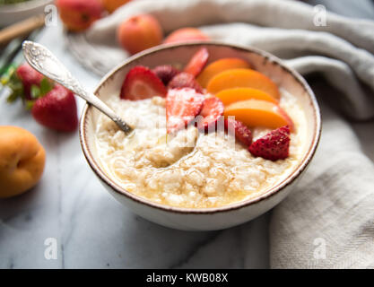 Warmes Müsli Schüssel serviert mit frischen Pfirsichen und Erdbeeren für ein gesundes Frühstück Stockfoto