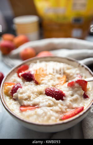 Warmes Müsli Schüssel serviert mit frischen Pfirsichen und Erdbeeren für ein gesundes Frühstück Stockfoto
