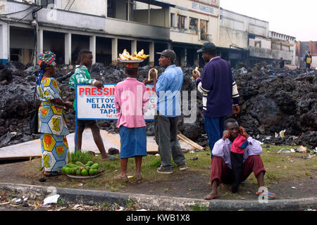 Wenn der Nyriragongo Vulkan auf 18/01/2002 ausbrach, Lava floss in Goma in der Demokratischen Republik Kongo, zerstören ein Drittel der Stadt. Obst Verkäufer sammeln am Rande der Lava entlang eines der Hauptziele von Goma Straßen. Stockfoto