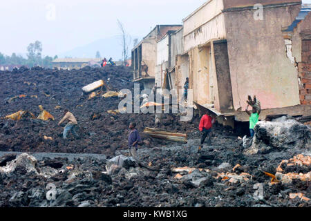 Wenn der Nyriragongo Vulkan auf 18/01/2002 ausbrach, Lava floss in Goma in der Demokratischen Republik Kongo, zerstören ein Drittel der Stadt. Menschen, die über die Kühlung lava Spülpumpe was können sie von den zerstörten Gebäuden. Stockfoto