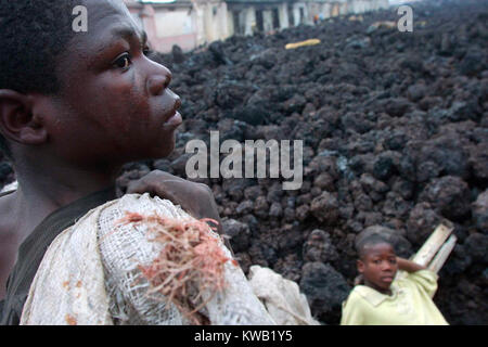 Wenn der Nyriragongo Vulkan auf 18/01/2002 ausbrach, Lava floss in Goma in der Demokratischen Republik Kongo, zerstören ein Drittel der Stadt. Menschen, die über die Kühlung lava Spülpumpe was können sie von den zerstörten Gebäuden. Stockfoto