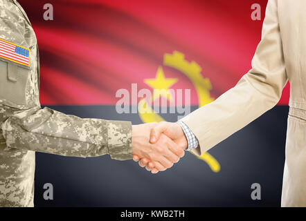 Amerikanischer Soldat in Uniform und Zivil Mann in Anzug Händeschütteln mit angemessene nationale Flagge auf Hintergrund - Angola Stockfoto