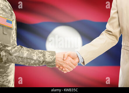 Amerikanischer Soldat in Uniform und Zivil Mann in Anzug Händeschütteln mit angemessene nationale Flagge auf Hintergrund - Laos Stockfoto