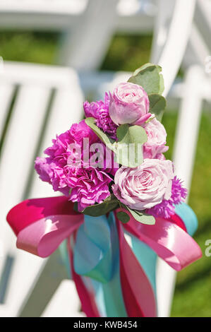 Reihe der weißen Stühlen in einem luxuriösen Hochzeitsfeier mit Blumenschmuck auf warmen sonnigen Tag. Stockfoto