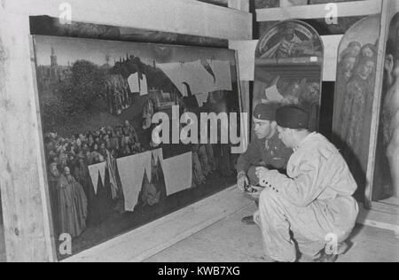 Soldaten der US-Armee MFAA Abschnitt Prüfung der Genter Altarbild in der altausseer Mine, 1945. Lt Daniel J. Kern und Deutschen Restaurator Karl Sieber untersuchen, Jan van Eyck's 'Anbetung der mystischen Lamm', ein Panel aus dem Altarbild geplündert von Deutschen aus Belgien im Jahre 1940. Weitere Panels von der zerlegten Altar sind auf der rechten Seite. Dieses Kunstwerk wurde in den Denkmälern Männer, einen Film 2014 auf Robert M. Edsel Buch basiert. Weltkrieg 2. (BSLOC 2014 10 282) Stockfoto