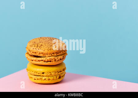 Ein Haufen leckeren Macarons von verschiedenen Geschmacksrichtungen auf einem Rosa und blauen Hintergrund mit einem leeren Raum auf der rechten Seite Stockfoto