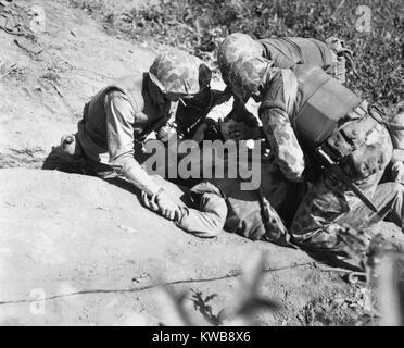 Us-Marine ist ein Schluck Wasser gegeben, wie er für die Evakuierung auf einen hinteren Bereich Hilfe Station wartet. 07.11.1952. Er war in erbitterten Kämpfen am Haken Ridge, wo zurück warf Marines ein Angriff von 800 chinesischen Soldaten verwundet. Koreakrieg, 1950-1953. (BSLOC 2014 11 190) Stockfoto