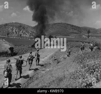 Us-Marines Vorrücken in der Naktong Fluss Schlacht, Sept. 4, 1950. Die Männer in der Spalte werden gestaffelt Opfer zu vermeiden und um die brennenden Nordkoreanischen Tank laufen. Zweiter von links Marine trägt einen Flammenwerfer, und der Mann vor ihm hat ein Raketenwerfer. Schlacht von Pusan Perimeter. Koreakrieg, 1950-1953. (BSLOC 2014 11 25) Stockfoto