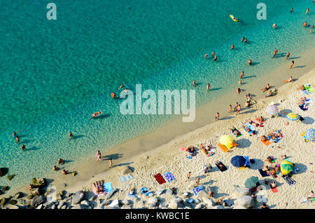 Menschen beim Sonnenbaden auf der sonnigen Strand von Santa Maria dell'Isola. Blick von L'Affaccio, einem Aussichtspunkt in der Altstadt. Tropea, Italien Stockfoto