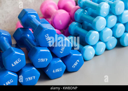 Blau und Rosa Hanteln liegen auf dem grauen Fußboden. Studio shot Stockfoto