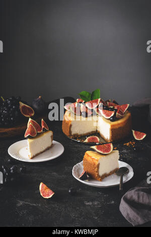 Käsekuchen mit Feigen. In Scheiben geschnitten New York Cheesecake auf dunklem Stein Hintergrund. Selektiver Fokus, getönten Bild Stockfoto