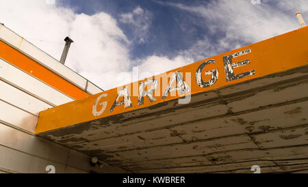 Das Wort Garage in abgeplatzte Farbe ziert ein verlassenes Gebäude mit blauem Himmel Hintergrund Stockfoto