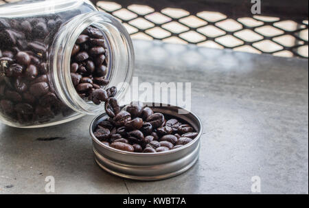 Nahaufnahme von Kaffeebohnen in Flaschenverschluss und Flasche auf Betonboden im Coffee Shop mit kopieren. Stockfoto