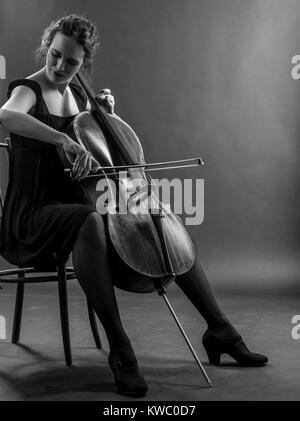 Foto von einem schönen weiblichen Musiker spielt ein Cello. Schwarz / weiß Bild. Stockfoto