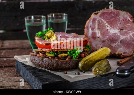 Hausgemachte Roggen Sandwich mit Schinken, Tomate, Zwiebel Marmelade, Essiggurken und Wodka. Stockfoto