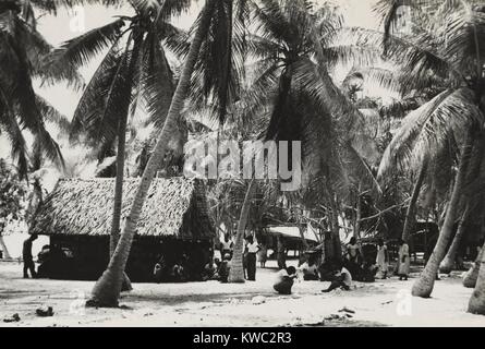 Bikini Inselbewohner in der Nähe von reetgedeckten Dach Gebäude im Schatten von Palmen, Ca. März 1946. 167 Inselbewohner von 40 Familien waren erforderlich, um Rongerik Atoll von US-Militär zu bewegen, bevor mit der Kreuzung Atombombe Tests von Juli 1946. (BSLOC 2015 2 2 9) Stockfoto