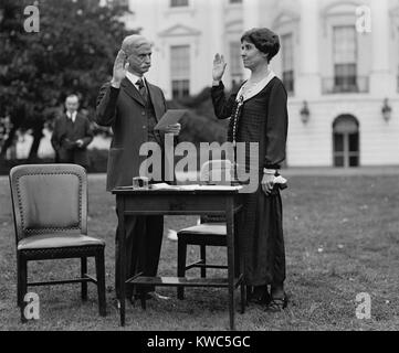 First Lady Grace Coolidge unter Eid vor dem Ausfüllen ihren Stimmzettel für die Wahl 1924. Präsident Calvin Coolidge steht im Hintergrund. (BSLOC 2015 15 117) Stockfoto