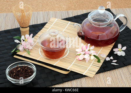 Kuchika Japanische gerösteten grünen Zweig Tee mit Glas Teekanne und Tassen, getrocknete Zweige, Rührer, Schneebesen und blühen Blumen hat viele gesundheitliche Vorteile. Stockfoto