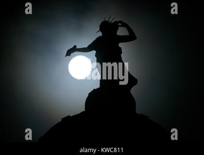 Das neue Jahr supermoon - auch als Wolf Mond - dargestellt in vollen Zügen mitten in der Nacht des 2. Januar hinter Bronze Thomas Clapperton Statue namens Literatur, die auf der Oberseite des Mitchell Library, Glasgow, Schottland sitzt bekannt. Stockfoto