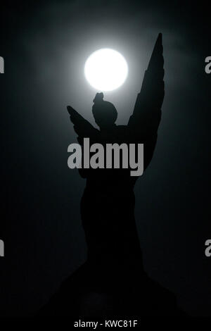 Das neue Jahr supermoon - auch als Wolf Mond - dargestellt in vollen Zügen mitten in der Nacht des 2. Januar hinter der Engel Statue auf dem Paisley Maut 'Engel Gebäude" über "La Fiorentina" Italienisches Restaurant in Glasgow in Schottland bekannt. Stockfoto