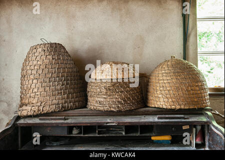 Die Lost Gardens of Heligan, Cornwall, UK. Alte Stroh Bienenstöcke (skeps) auf einem Schreibtisch im Büro Der alte Gärtner Stockfoto