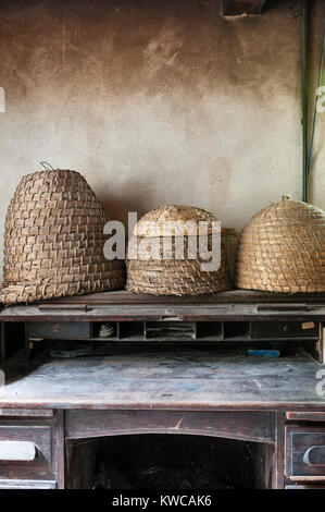 Die Lost Gardens of Heligan, Cornwall, UK. Alte Stroh Bienenstöcke (skeps) auf einem Schreibtisch im Büro Der alte Gärtner Stockfoto