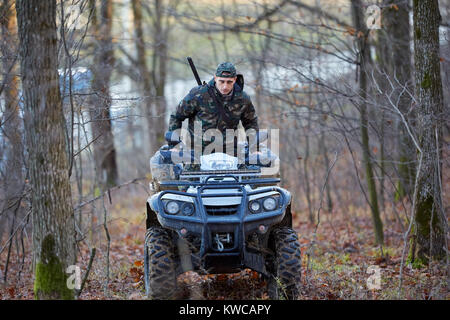 Junge Jäger auf ein Quad auf der Suche nach Spiel im Wald Stockfoto