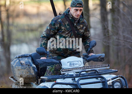 Junge Jäger auf ein Quad auf der Suche nach Spiel im Wald Stockfoto