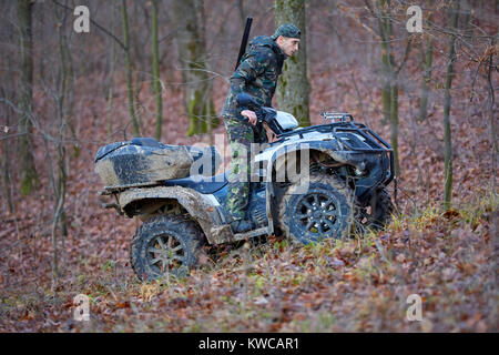 Junge Jäger auf ein Quad auf der Suche nach Spiel im Wald Stockfoto