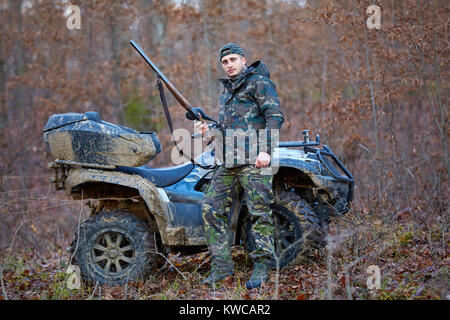 Junge Jäger auf ein Quad auf der Suche nach Spiel im Wald Stockfoto