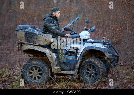 Junge Jäger auf ein Quad auf der Suche nach Spiel im Wald Stockfoto