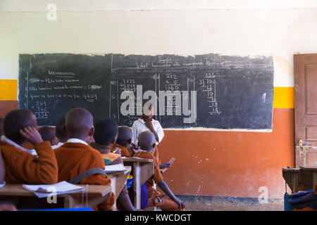 Kinder in Uniformen in der Grundschule Klassenzimmer listetning zu Lehrer in ländlicher Umgebung in der Nähe von Arusha, Tansania, Afrika. Stockfoto