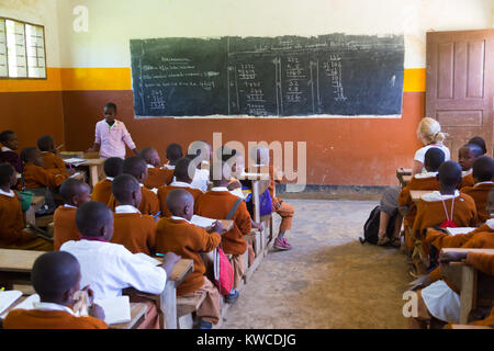 Kinder in Uniformen in der Grundschule Klassenzimmer listetning zu Lehrer in ländlicher Umgebung in der Nähe von Arusha, Tansania, Afrika. Stockfoto