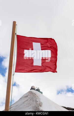 Schweizer Fahne am Jungfraujoch mit Sphinx observartory im Hintergrund. Jungfraujoch, Berner Oberland, Schweiz Stockfoto