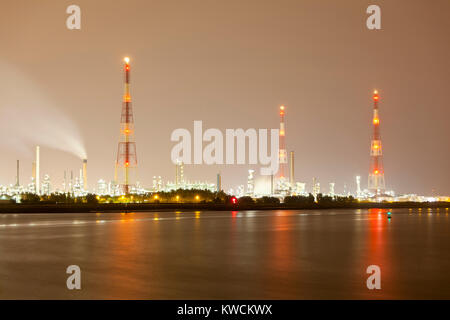 Eine Ölraffinerie mit hohen Gas flare Stacks in einem Hafen mit schmutzigen Nachthimmel. Stockfoto