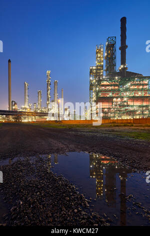 Eine Ölraffinerie im Hafen von Antwerpen in der Nacht mit Reflektion in einer Pfütze. Stockfoto