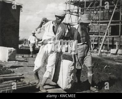 Zwei chinesische Männer arbeiten zusammen, um einen großen Stein auf einer Baustelle leben. Sie verwenden traditionellen vorindustriellen Hebetechniken. Ca. 1930-40 s. - (BSLOC 2014 15 151) Stockfoto
