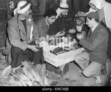 Arabische Palästinenser untersuchen Waffen in einem Jerusalem Markt. Waffen, Munition, und Handgranaten waren zum Verkauf neben Gemüse am 1. März 1948. - (BSLOC 2014 15 202) Stockfoto