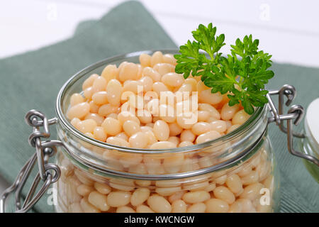 Jar in der Dose weiße Bohnen auf grauer Unterlage - Nahaufnahme Stockfoto